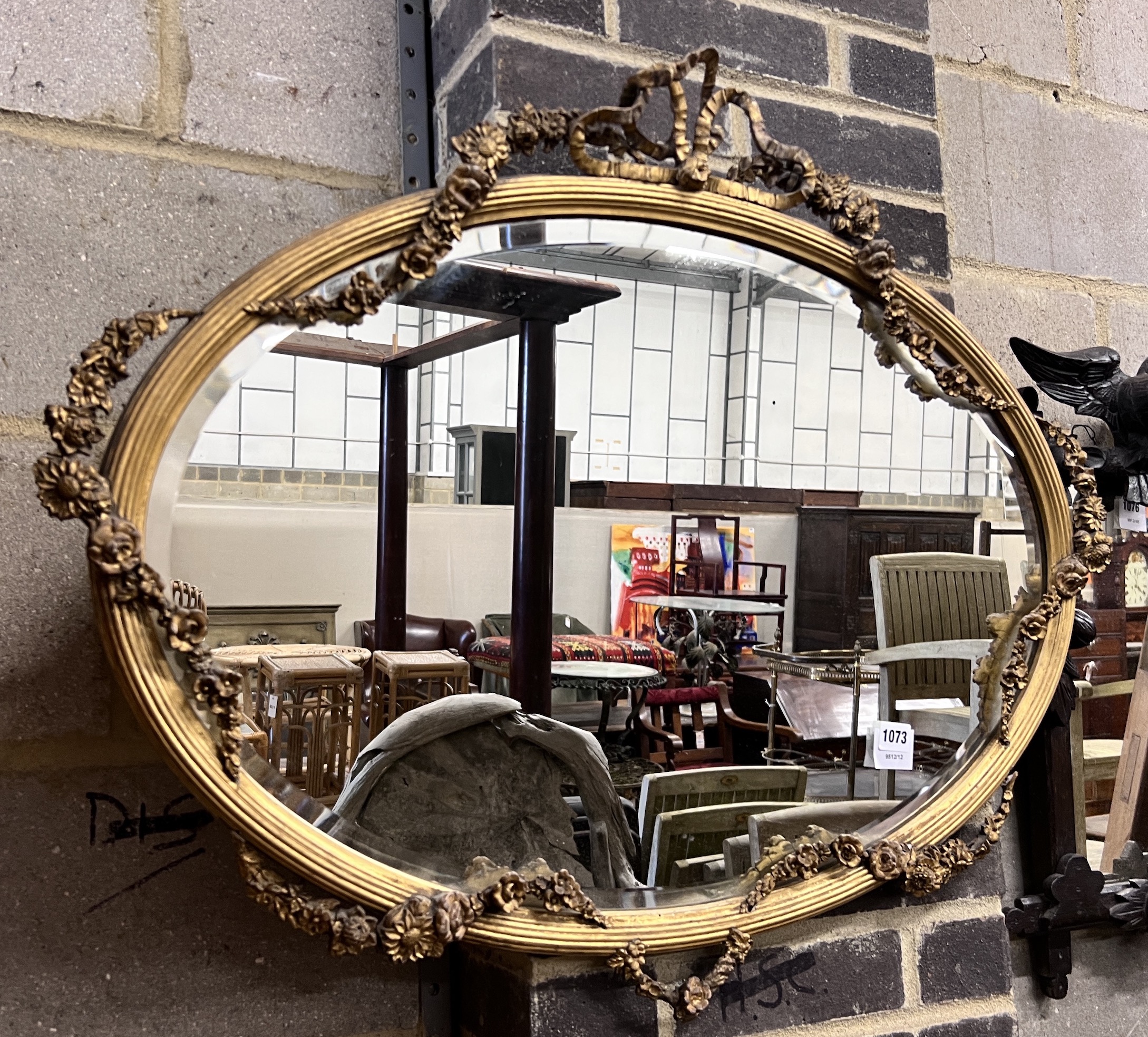 An Edwardian oval giltwood and gesso wall mirror with ribbon and flower swagged border, width 87cm, height 68cm